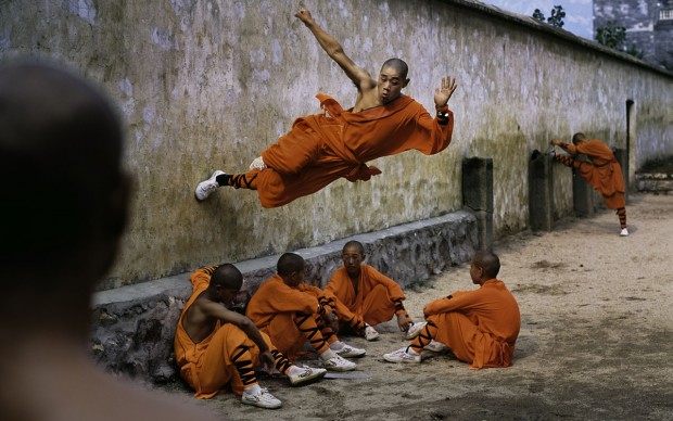 Steve McCurry - Un giovane monaco corre lungo un muro sopra i suoi compagni. Shaolin Monastery, Hunan Province, China; 2004 © St. Moritz Art Masters 2013