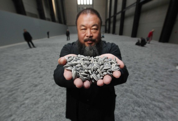 Ai Weiwei mostra alcuni dei "Sunflower Seeds" in porcellana che compongono l'omonima installazione in mostra alla Tate Modern di Londra, dall'ottobre del 2010 a maggio 2011 (Photo by Peter Macdiarmid/Getty Images)
