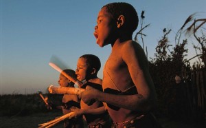 Chris Johns, Lukulu - Zambia, 1996. Ragazzi della tribù Luvale salutano l’alba con canti e percussioni tradizionali nel villaggio di Lukulu, lungo il tratto superiore dello Zambesi. Il fotografo, Chris Johns, è diventato direttore del magazine americano nel 2005