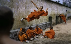Steve McCurry - Un giovane monaco corre lungo un muro sopra i suoi compagni. Shaolin Monastery, Hunan Province, China; 2004