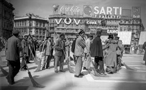 Comparse che interpretano degli spazzini fotografate in Piazza del Duomo durante la lavorazione di una scena del film Miracolo a Milano di Vittorio De Sica, 1951; ©ArchiviFarabola