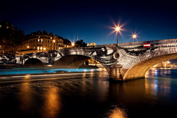 JR, 28 Millimètres, Women Are Heroes, Exhibition in Paris, Pont Louis-Philippe–Pont Marie Side by Night, with Barge, France, 2009. Color lithograph. © JR-ART.NET