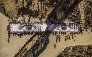 JR, Migrants, Mayra, Picnic across the Border, Tecate, Mexico - U.S.A., 2017. Installation image. Wheat-pasted poster on table © JR-ART.NET